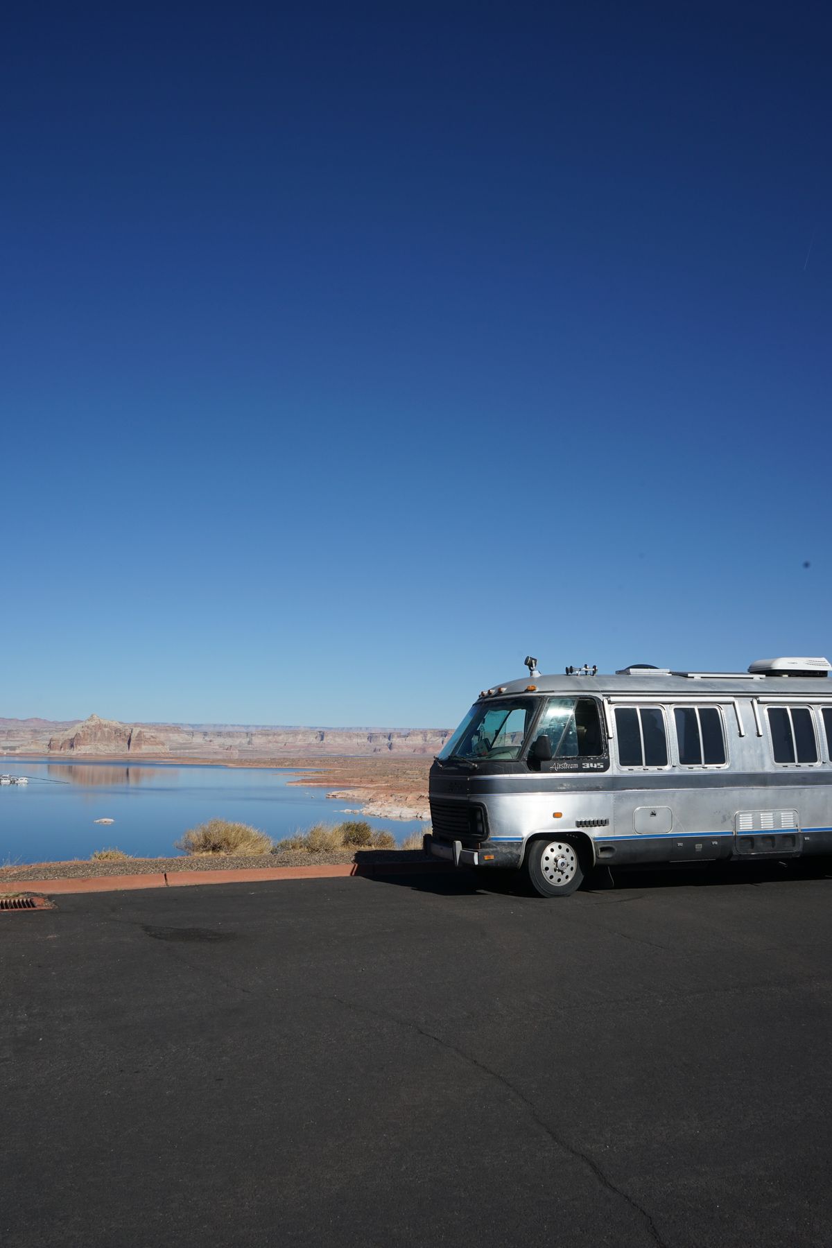 Vintage Airstream motorhome parked at an overlook above a desert lake in Arizona