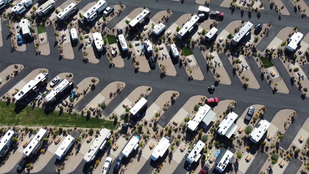 Aerial view of RVs and fifth wheels filling the landscaped rows of a sunny desert RV park