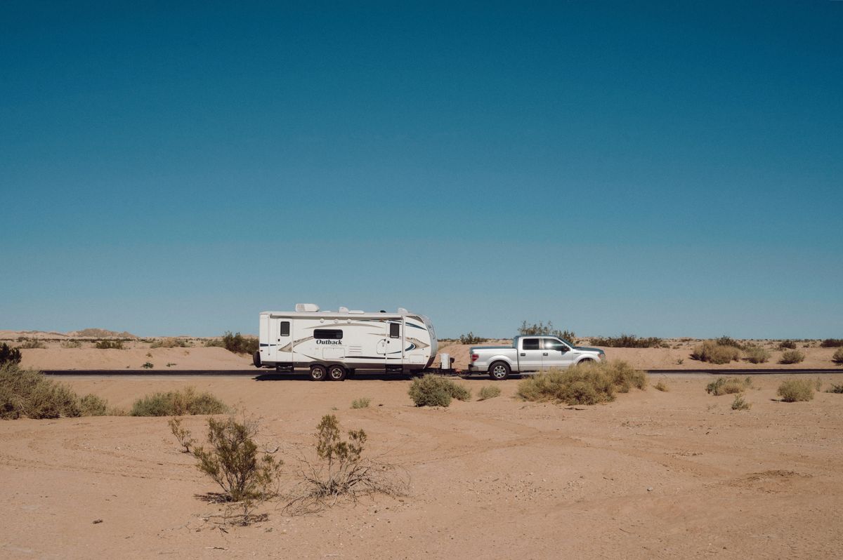Pickup truck and travel trailer parked on open desert flats scattered with creosote brush